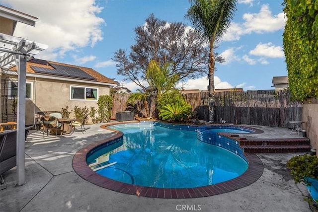 view of swimming pool with outdoor dining area, a pool with connected hot tub, a fenced backyard, and a patio area