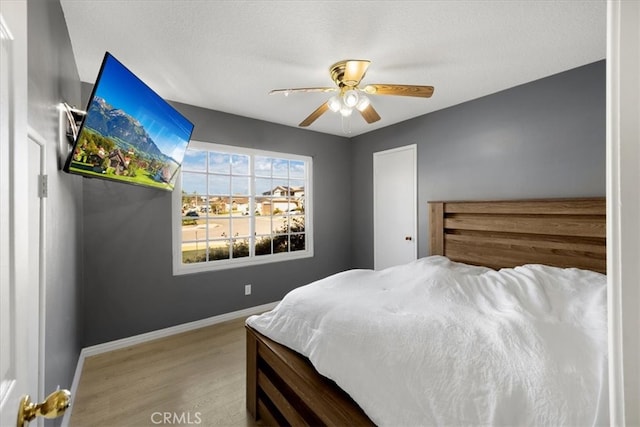 bedroom with baseboards, wood finished floors, and a ceiling fan