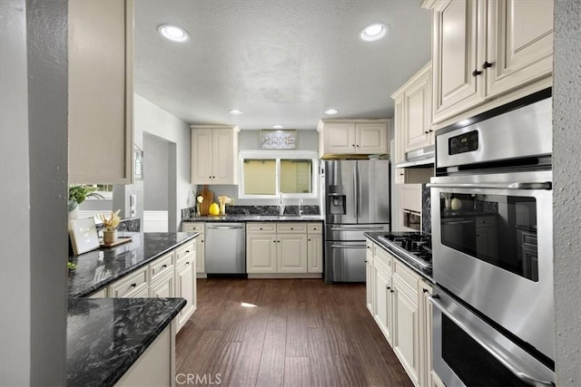 kitchen with dark stone countertops, recessed lighting, dark wood-type flooring, appliances with stainless steel finishes, and exhaust hood