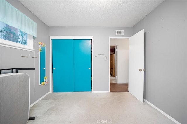 unfurnished bedroom with baseboards, visible vents, a textured ceiling, and carpet