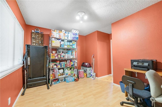 home office featuring baseboards, plenty of natural light, a textured ceiling, and wood finished floors