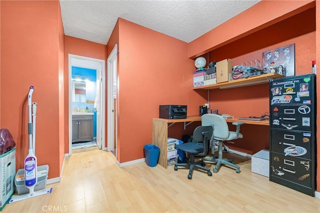 office with a sink, a textured ceiling, baseboards, and wood finished floors