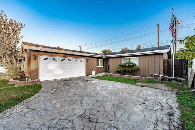 ranch-style house featuring fence, a garage, and driveway