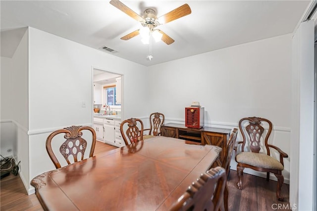 dining room featuring visible vents, ceiling fan, and wood finished floors