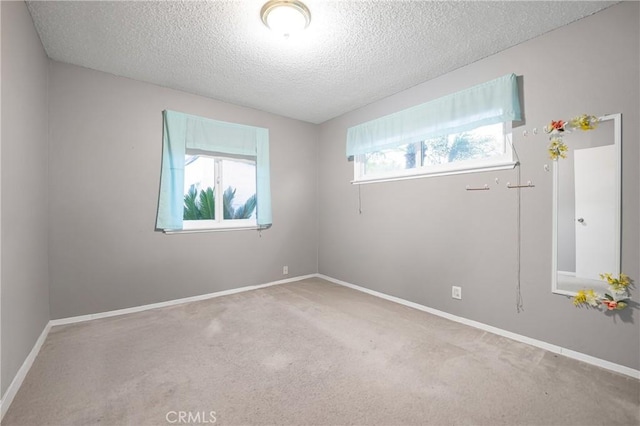 carpeted empty room with baseboards and a textured ceiling