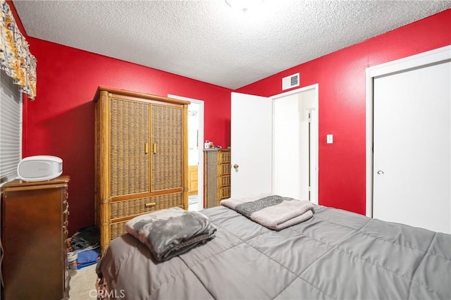 bedroom with visible vents, a textured ceiling, a closet, and carpet