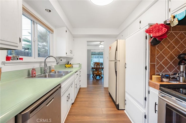 kitchen featuring white cabinetry, freestanding refrigerator, a sink, stainless steel dishwasher, and light wood-type flooring