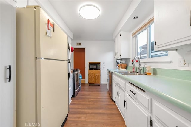 kitchen featuring a sink, wood finished floors, stainless steel appliances, white cabinets, and light countertops