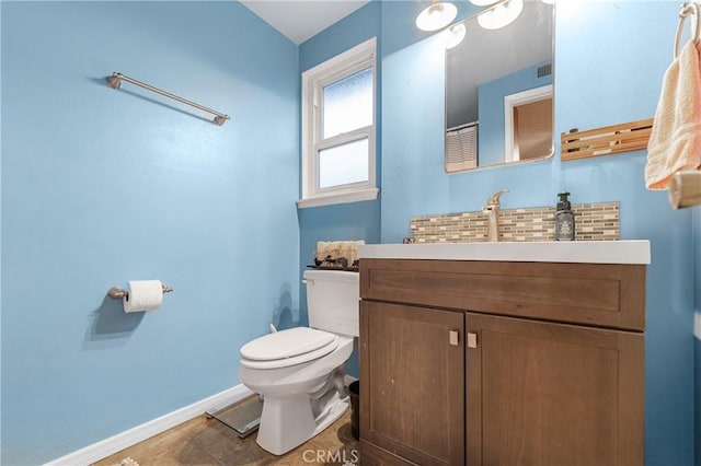 bathroom with toilet, vanity, and baseboards