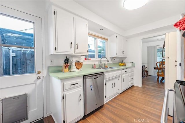 kitchen with light countertops, light wood-type flooring, stainless steel dishwasher, white cabinetry, and a sink