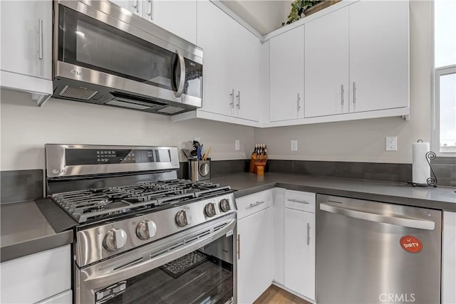 kitchen with dark countertops, white cabinetry, and stainless steel appliances