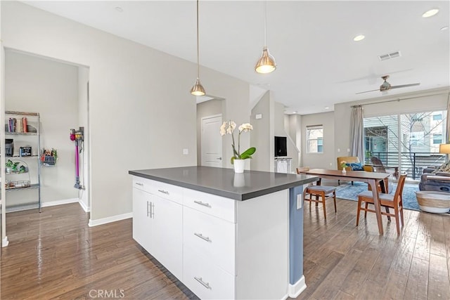 kitchen featuring dark countertops, white cabinetry, a center island, and dark wood-style flooring