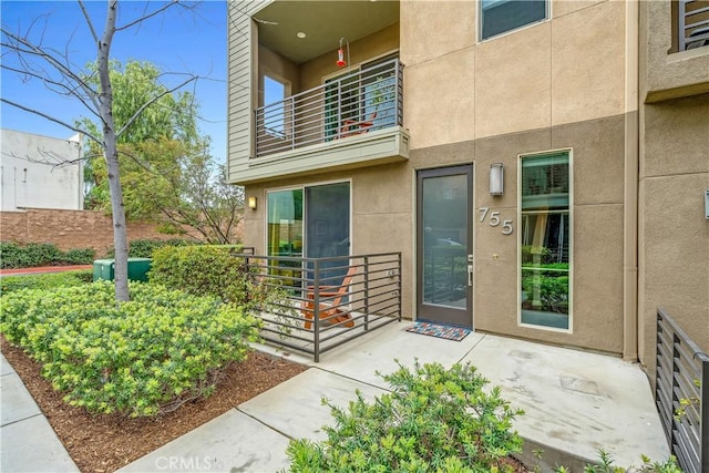 entrance to property with stucco siding and a balcony