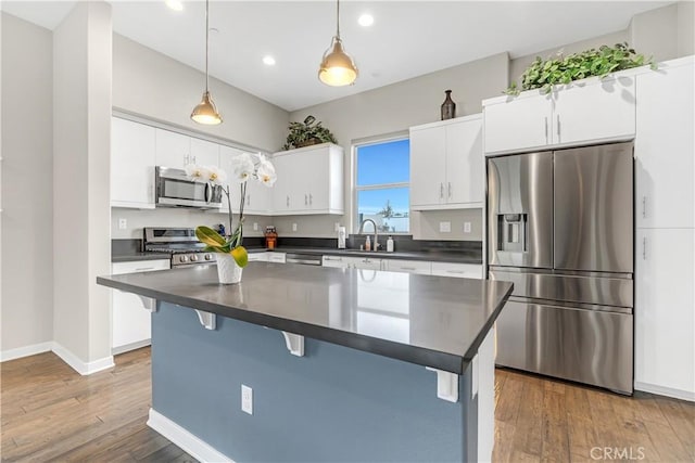 kitchen with dark wood-style floors, dark countertops, appliances with stainless steel finishes, and a breakfast bar area