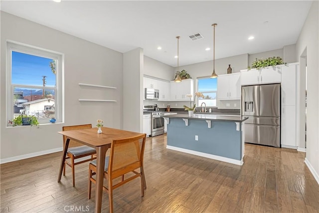 dining room with visible vents, baseboards, and hardwood / wood-style flooring