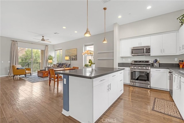 kitchen featuring dark countertops, open floor plan, appliances with stainless steel finishes, and hardwood / wood-style floors