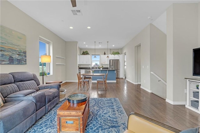 living area featuring visible vents, recessed lighting, dark wood-type flooring, and baseboards