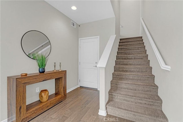 staircase with recessed lighting, wood finished floors, visible vents, and baseboards