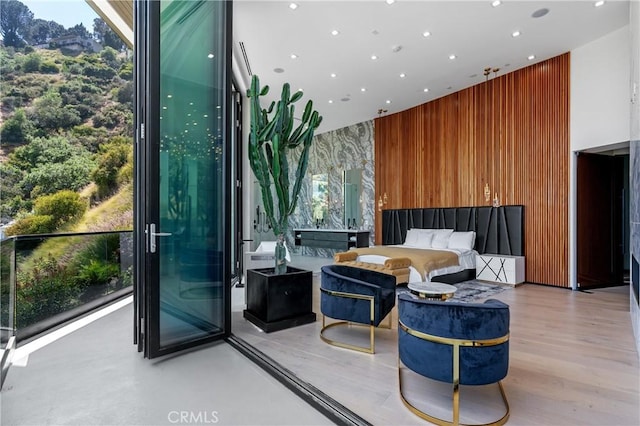 bedroom with wooden walls, recessed lighting, and a towering ceiling