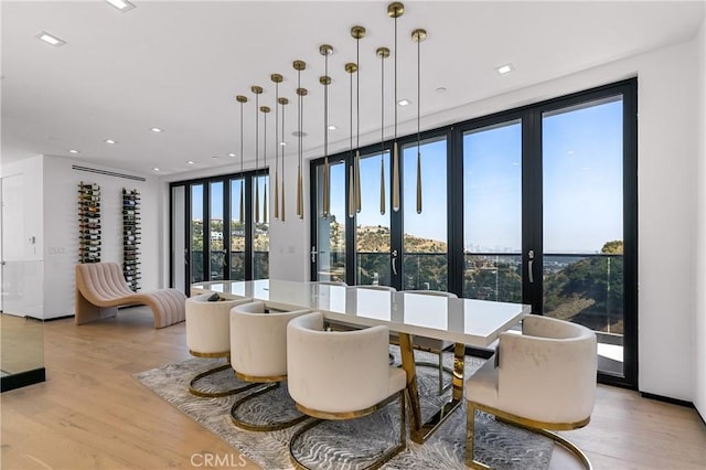 dining room featuring floor to ceiling windows, recessed lighting, and light wood-style floors