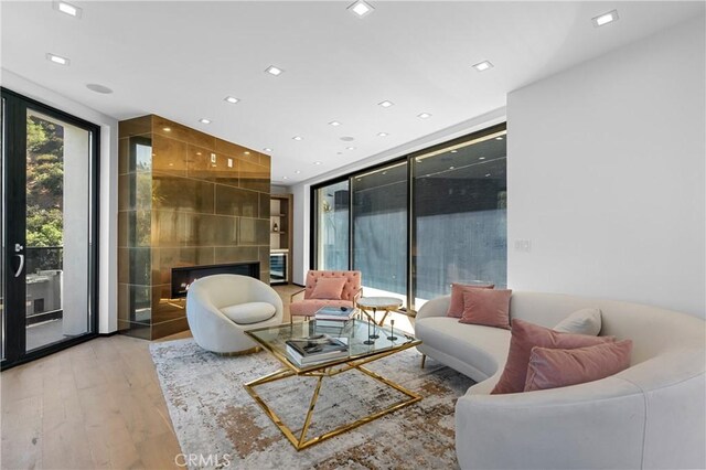 living room with recessed lighting, a large fireplace, floor to ceiling windows, and light wood finished floors