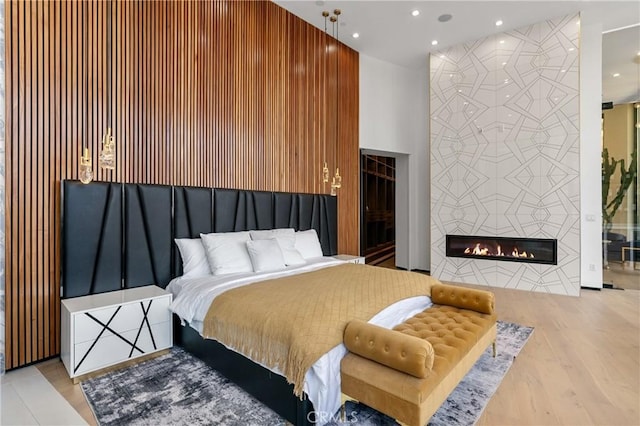 bedroom with an accent wall, wood finished floors, recessed lighting, and a fireplace