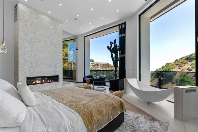 bedroom featuring access to outside, recessed lighting, and a tile fireplace