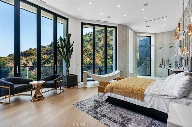 bedroom featuring recessed lighting, expansive windows, and wood finished floors