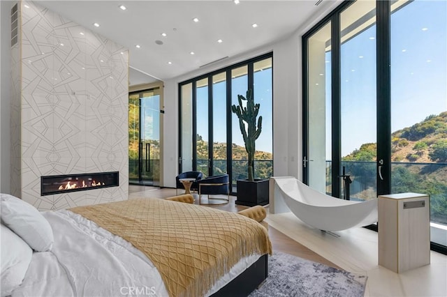 bedroom featuring floor to ceiling windows, access to outside, visible vents, and a tile fireplace