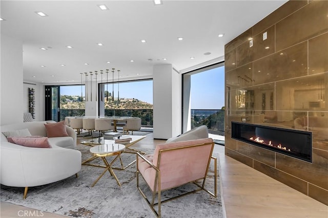 living room featuring recessed lighting, a tile fireplace, a wall of windows, and wood finished floors