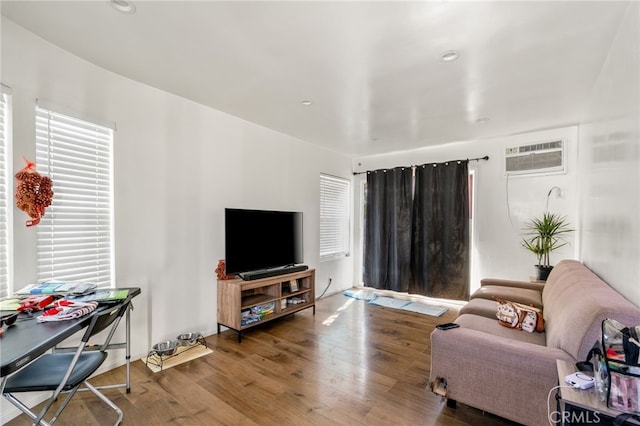 living area with recessed lighting, a wall mounted air conditioner, and wood finished floors