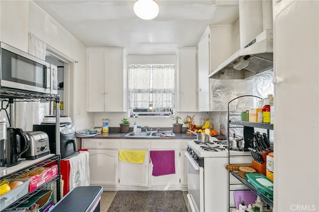 kitchen featuring white range with gas stovetop, a sink, white cabinetry, stainless steel microwave, and wall chimney exhaust hood