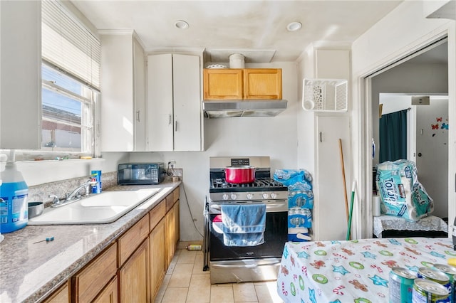 kitchen with light tile patterned floors, a sink, light countertops, under cabinet range hood, and gas range