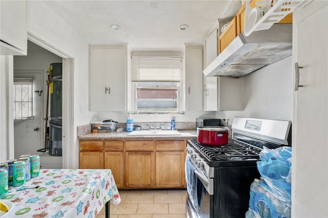 kitchen featuring light tile patterned floors, a sink, light countertops, under cabinet range hood, and stainless steel gas stove