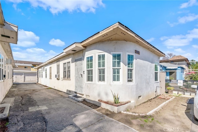 view of side of home with crawl space, fence, a garage, and stucco siding