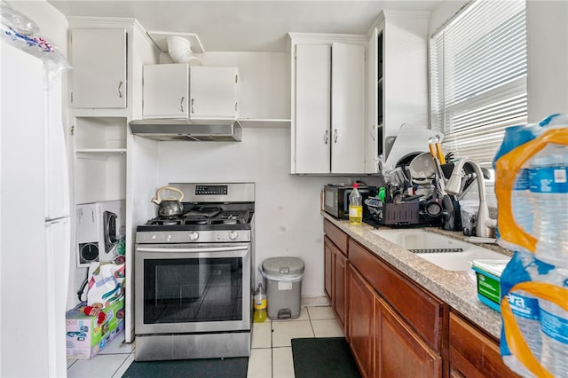 kitchen featuring under cabinet range hood, a sink, stainless steel range with gas cooktop, light tile patterned flooring, and light countertops