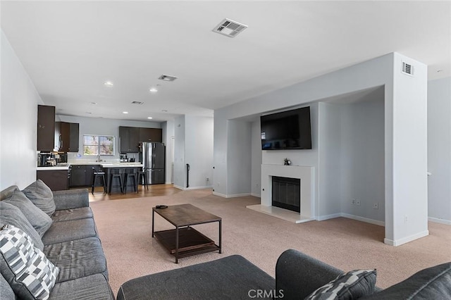 living area with visible vents, baseboards, and a glass covered fireplace