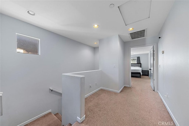 hall featuring carpet, an upstairs landing, visible vents, and baseboards