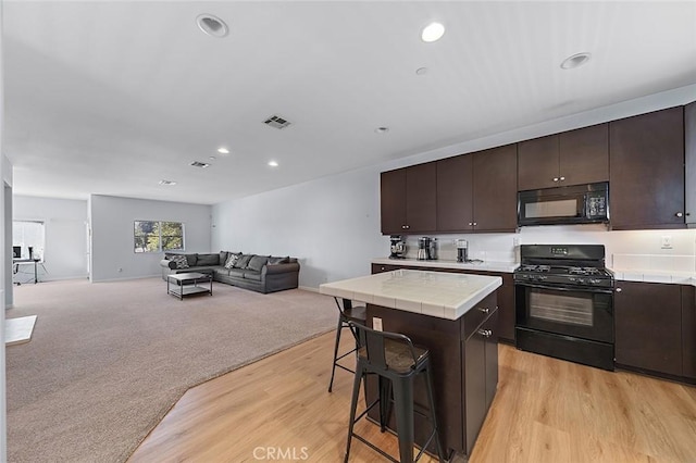 kitchen featuring light carpet, black appliances, open floor plan, tile countertops, and dark brown cabinets