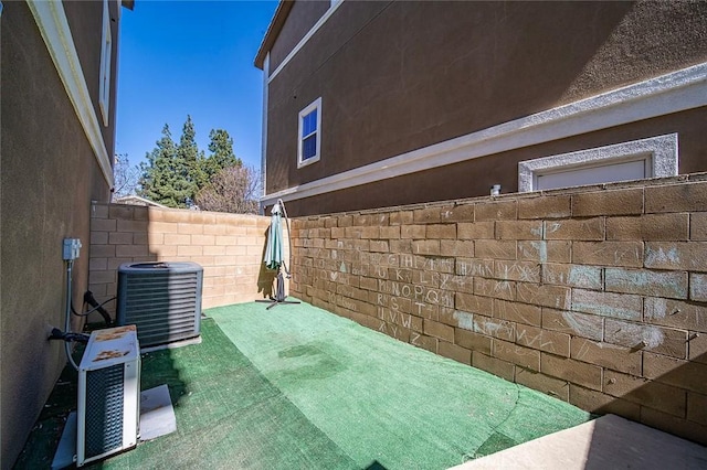 view of side of property with stucco siding, cooling unit, and fence