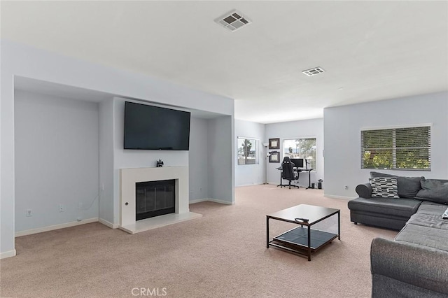 living room with a glass covered fireplace, baseboards, visible vents, and light carpet