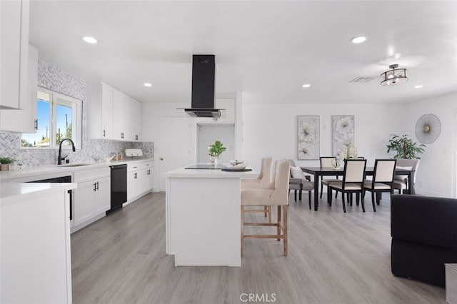 kitchen with a center island, ventilation hood, light wood-style flooring, a kitchen breakfast bar, and white cabinetry