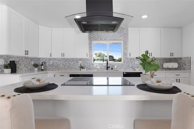 kitchen with decorative backsplash, island exhaust hood, light countertops, and a sink