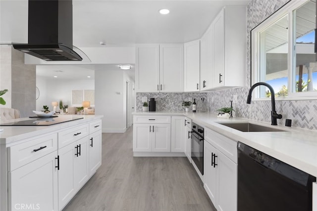 kitchen featuring black appliances, light wood-style flooring, a sink, exhaust hood, and light countertops