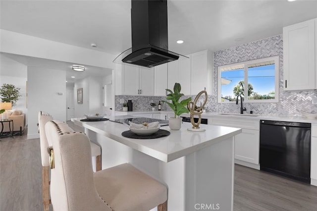 kitchen featuring black appliances, island exhaust hood, a sink, white cabinetry, and a breakfast bar area