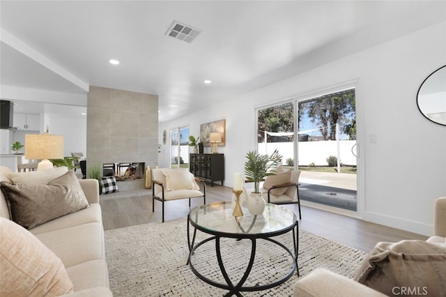 living area with recessed lighting, visible vents, light wood-style flooring, and baseboards