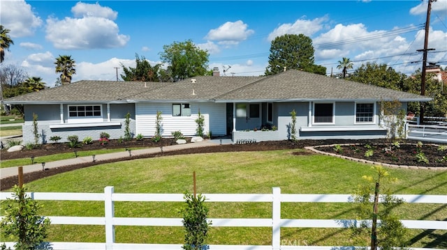 ranch-style home featuring stucco siding, a front lawn, fence, a shingled roof, and a chimney