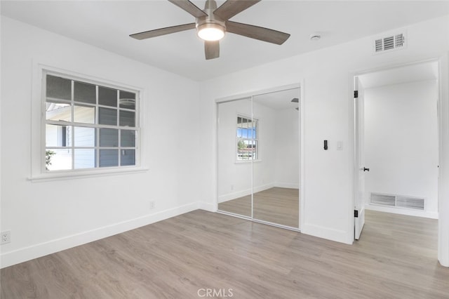 unfurnished bedroom with light wood finished floors, visible vents, and a closet