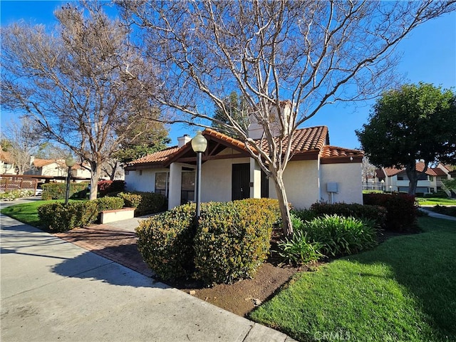 view of side of home with stucco siding, a tile roof, and a lawn