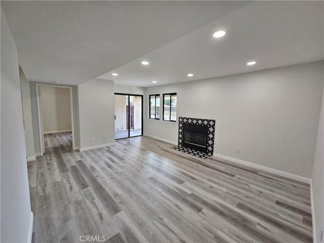 interior space featuring recessed lighting, light wood-type flooring, baseboards, and a tile fireplace